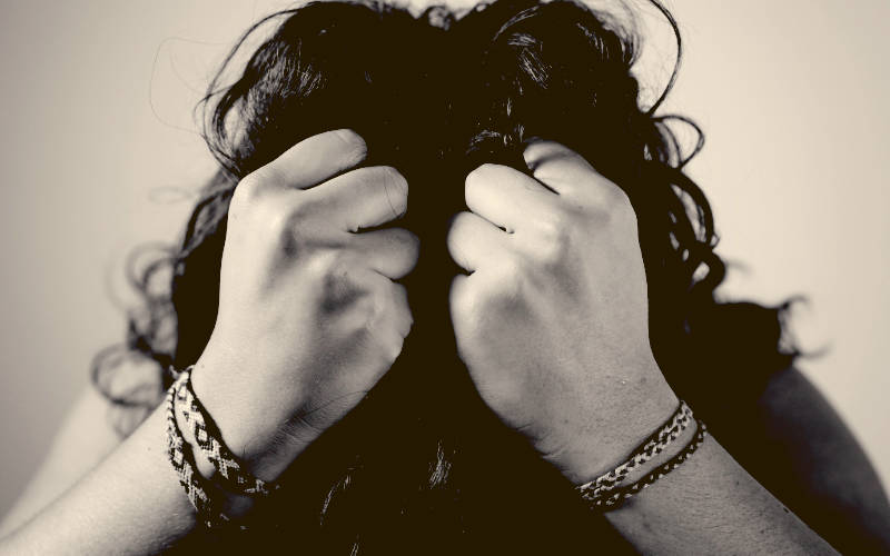 person with head in hands that are fists
